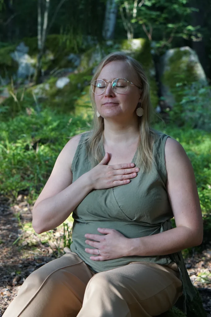 Kehotietoisuusharjoitus metsässä, kädet rinnalla ja vatsalla