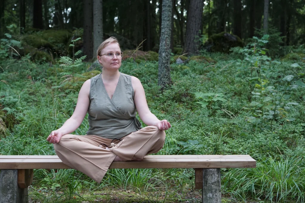 Meditaatio risti-istunnassa puupenkillä keskellä metsää