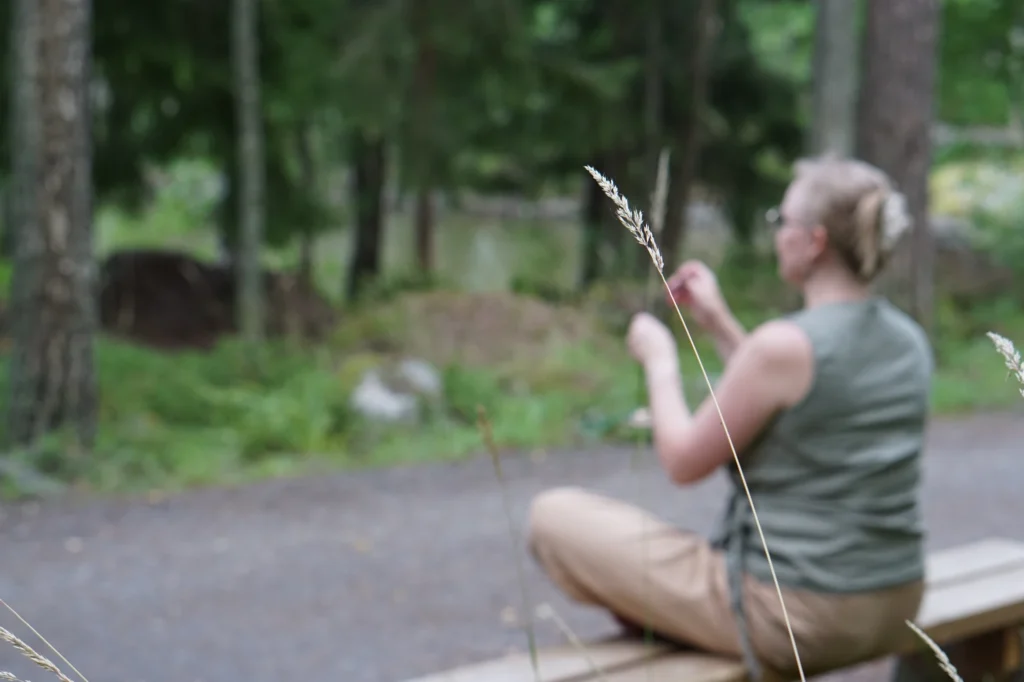 Tunnelmakuva metsämeditaatiosta, etualalla heinä ja taustalla meditoija